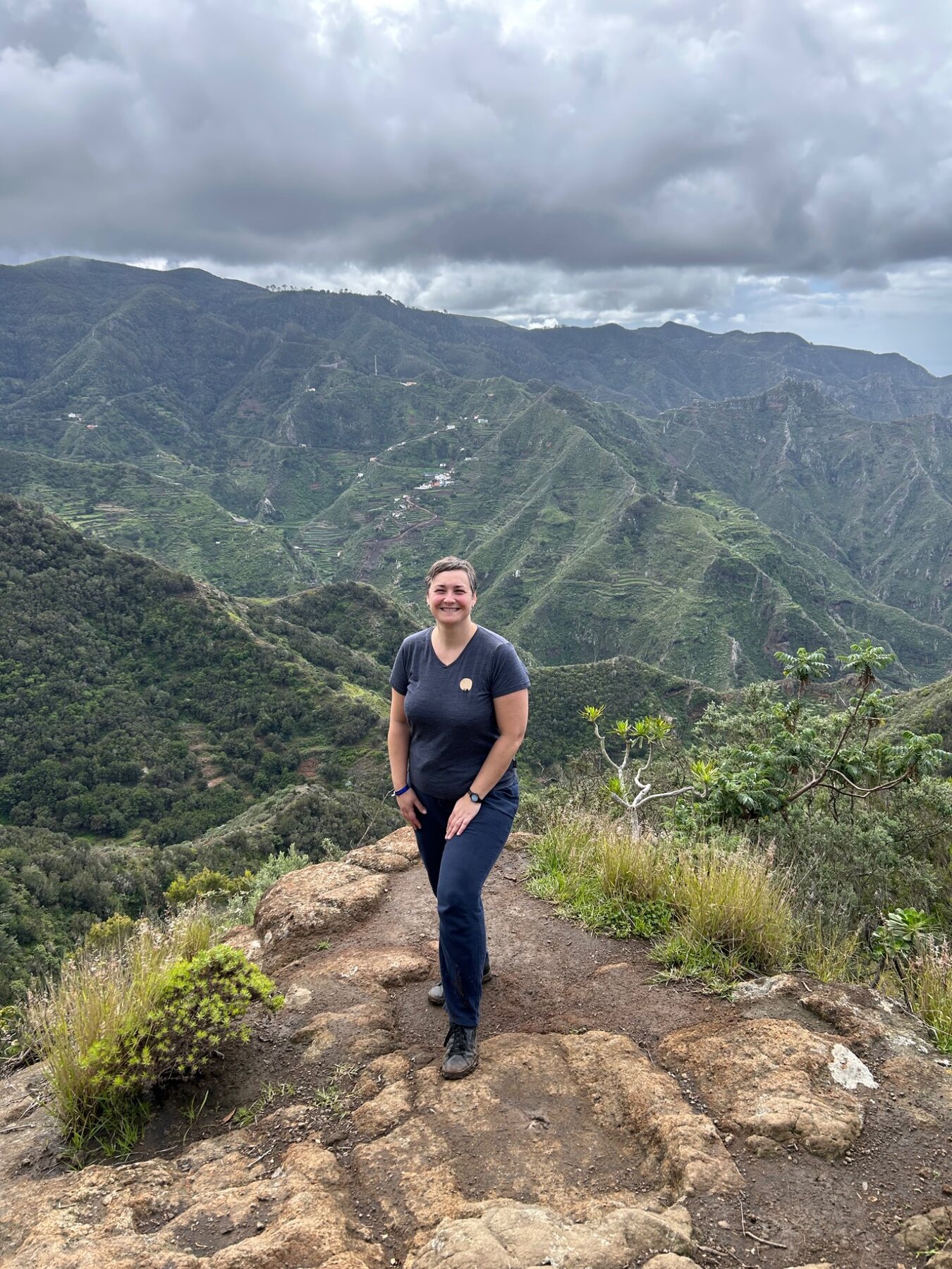 Dana Gutjahr auf einem Bergweg inmitten einer weiten grünen Landschaft.